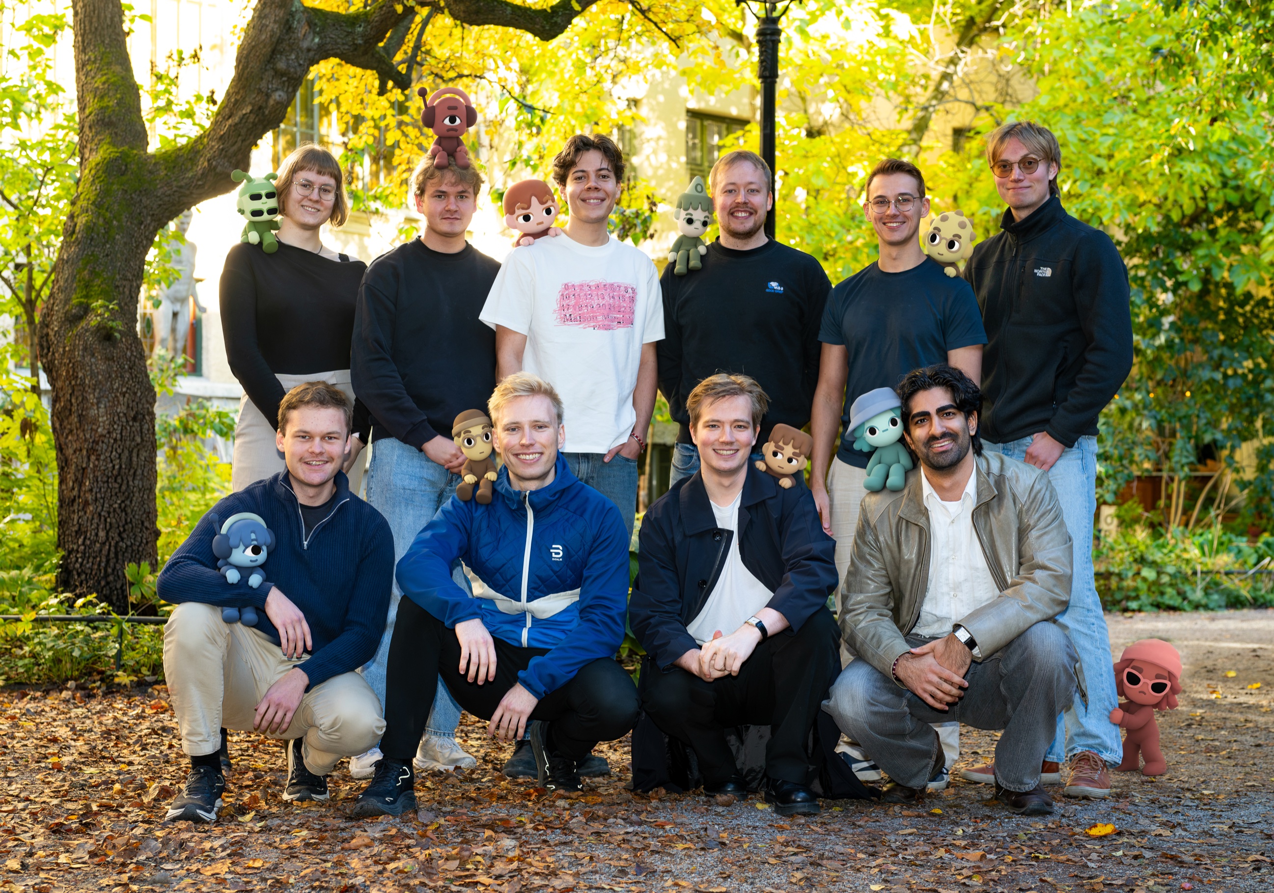 The Strawberry team, ten people outdoors under autumn trees, each with their own companion on a shoulder, head, or lap.